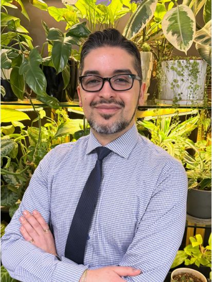 a smiling man in front of several plants.