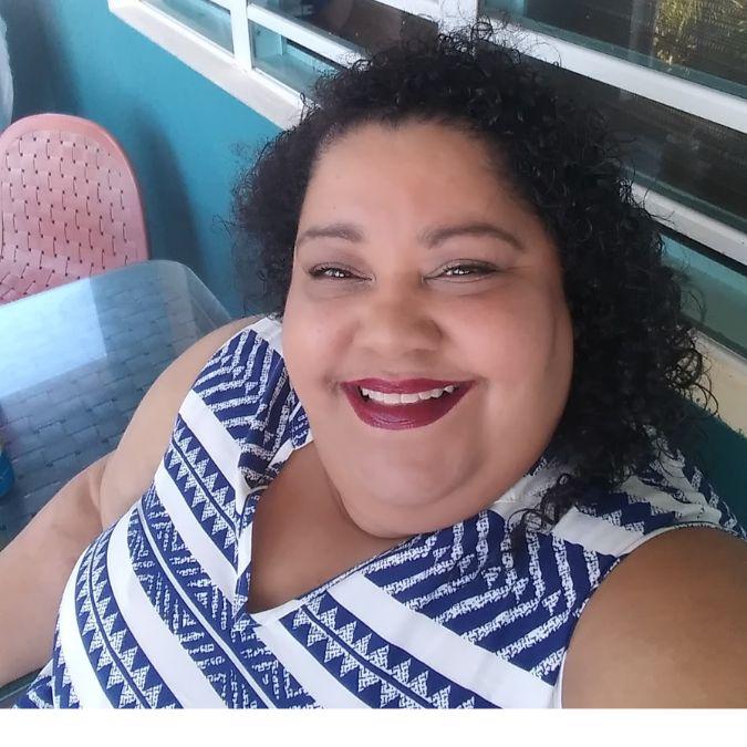 A smiling woman wearing a striped patterned shirt.