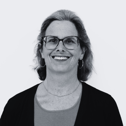 a black and white photo of a smiling woman wearing glasses