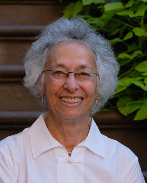 a smiling woman wearing glasses and a white shirt