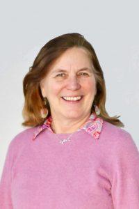 A smiling woman in front of a gray wall