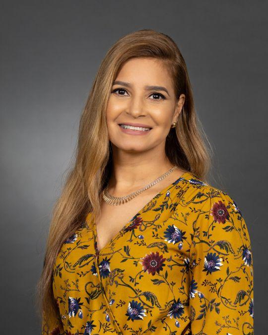 A smiling woman in front of a gray background