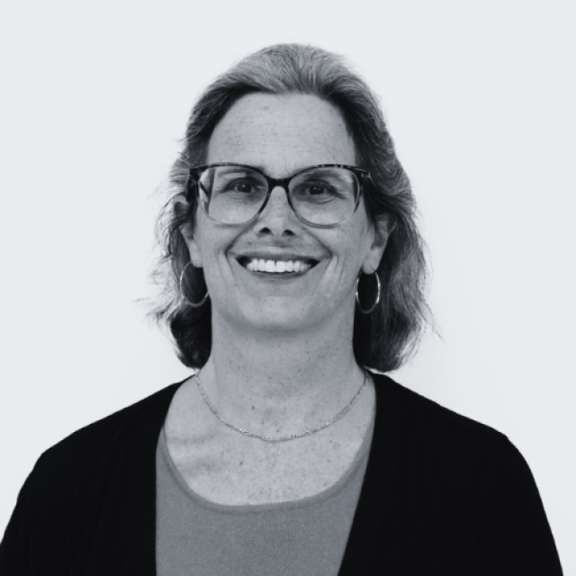 a black and white photo of a smiling woman wearing glasses