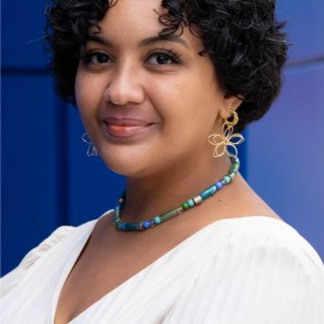 a woman in a white shirt in front of a blue background.