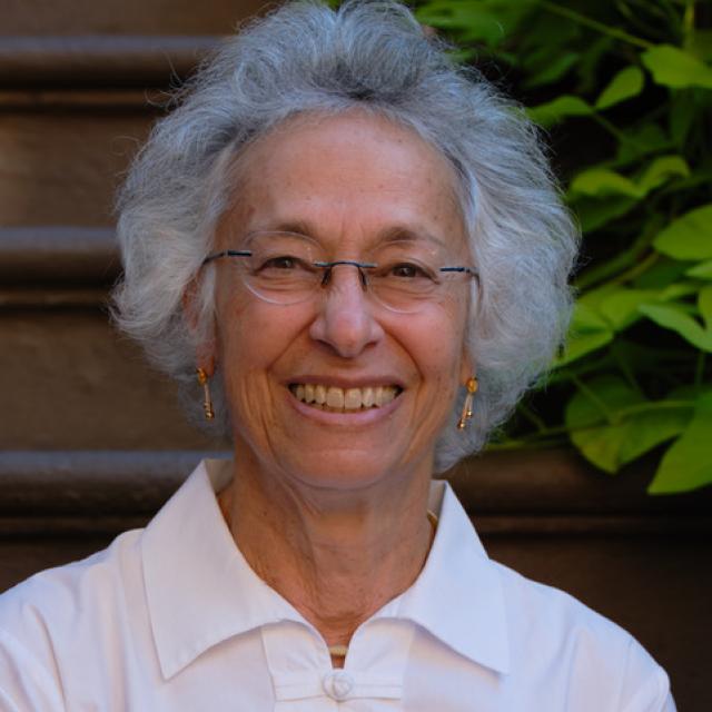 a smiling woman wearing glasses and a white shirt