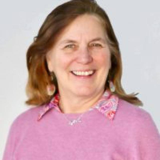A smiling woman in front of a gray wall