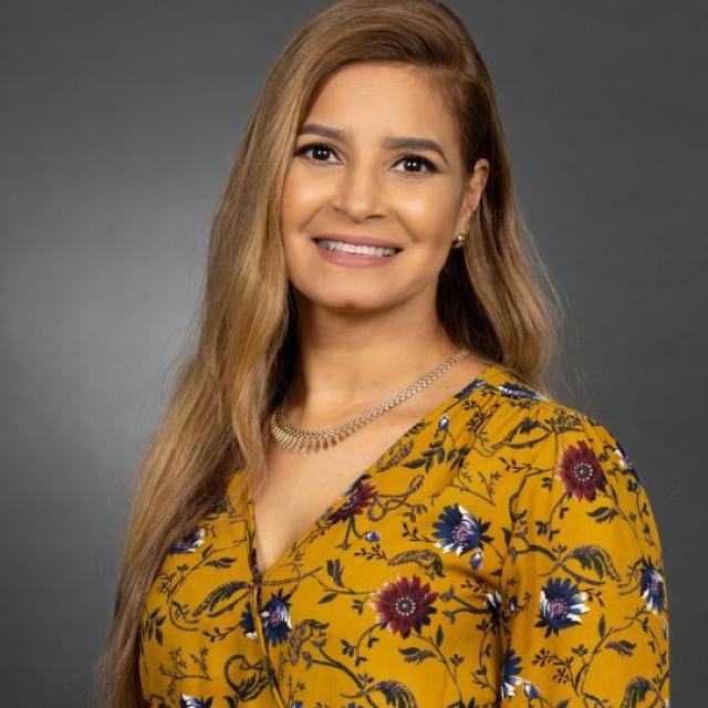 A smiling woman in front of a gray background